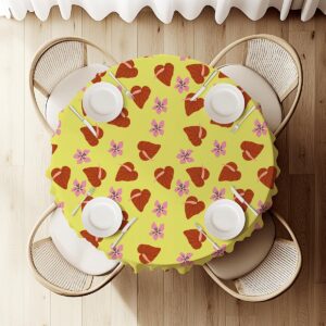 Widok z góry na okrągły stół przykryty obrusem z liściastymi sercami i różowymi kwiatami z nakryciami