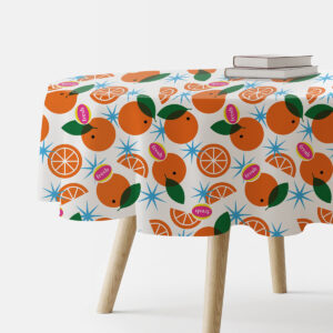 okrągły obrus z wzorem pomarańczy i gwiazdek na stole, widok boczny z książkami umieszczonymi na rancie