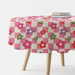Okrągły obrus z różowo-kremową kratą i kolorowymi kwiatami na stole, ujęcie boczne