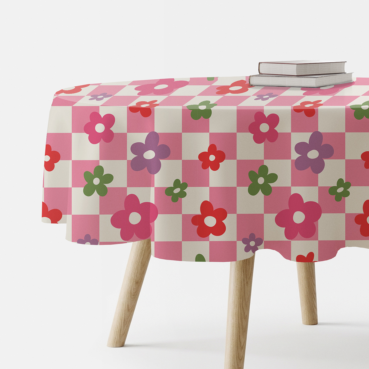Okrągły obrus z różowo-kremową kratą i kolorowymi kwiatami na stole, ujęcie boczne