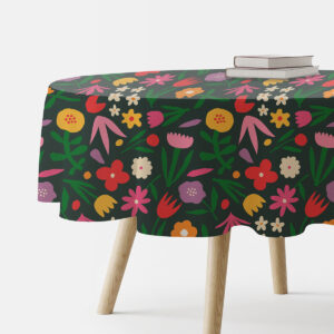 Okrągły obrus z żywym wzorem kwiatów na ciemnozielonym tle, widok boczny ze stosem książek