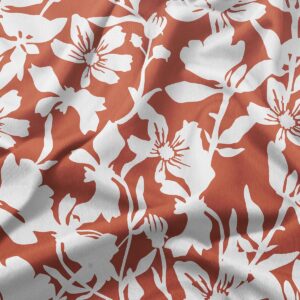 Zbliżenie na dekoracyjny biały motyw kwiatowy na ceglastym tle pokazujące fakturę tkaniny