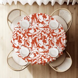 Widok z góry na okrągły obrus z kontrastowym, białym motywem kwiatowym na ceglastym tle