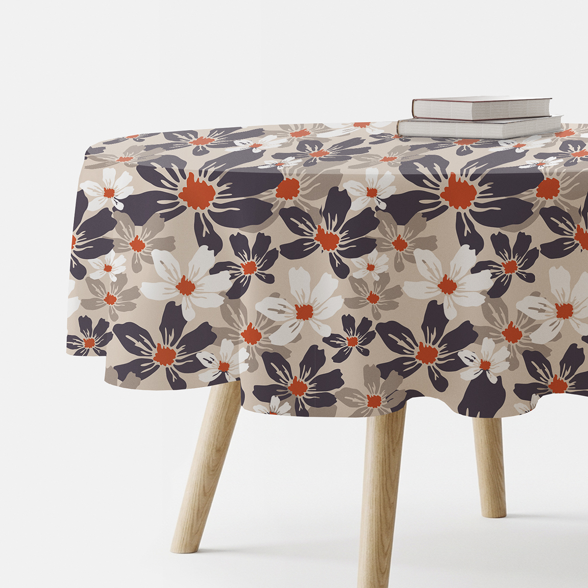 okrągły obrus na stole z beżowym tłem i dużym kwiatowym wzorem, ujęcie produktu z boku z książkami na blacie