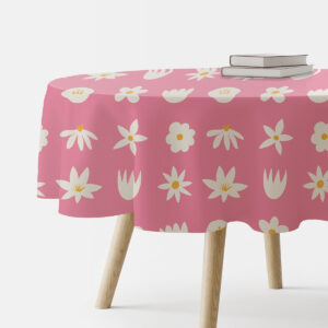 okrągły obrus w różowym tle z białymi stokrotkami na stole z książkami