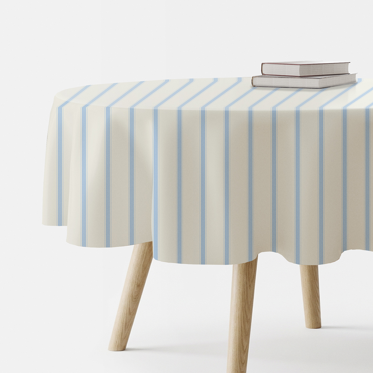 okrągły obrus kremowy z pionowymi błękitnymi pasami na stole