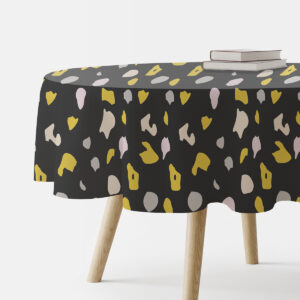 okrągły obrus na stole z widocznym grafitowym tłem i musztardowo-pudrowym wzorem terrazzo