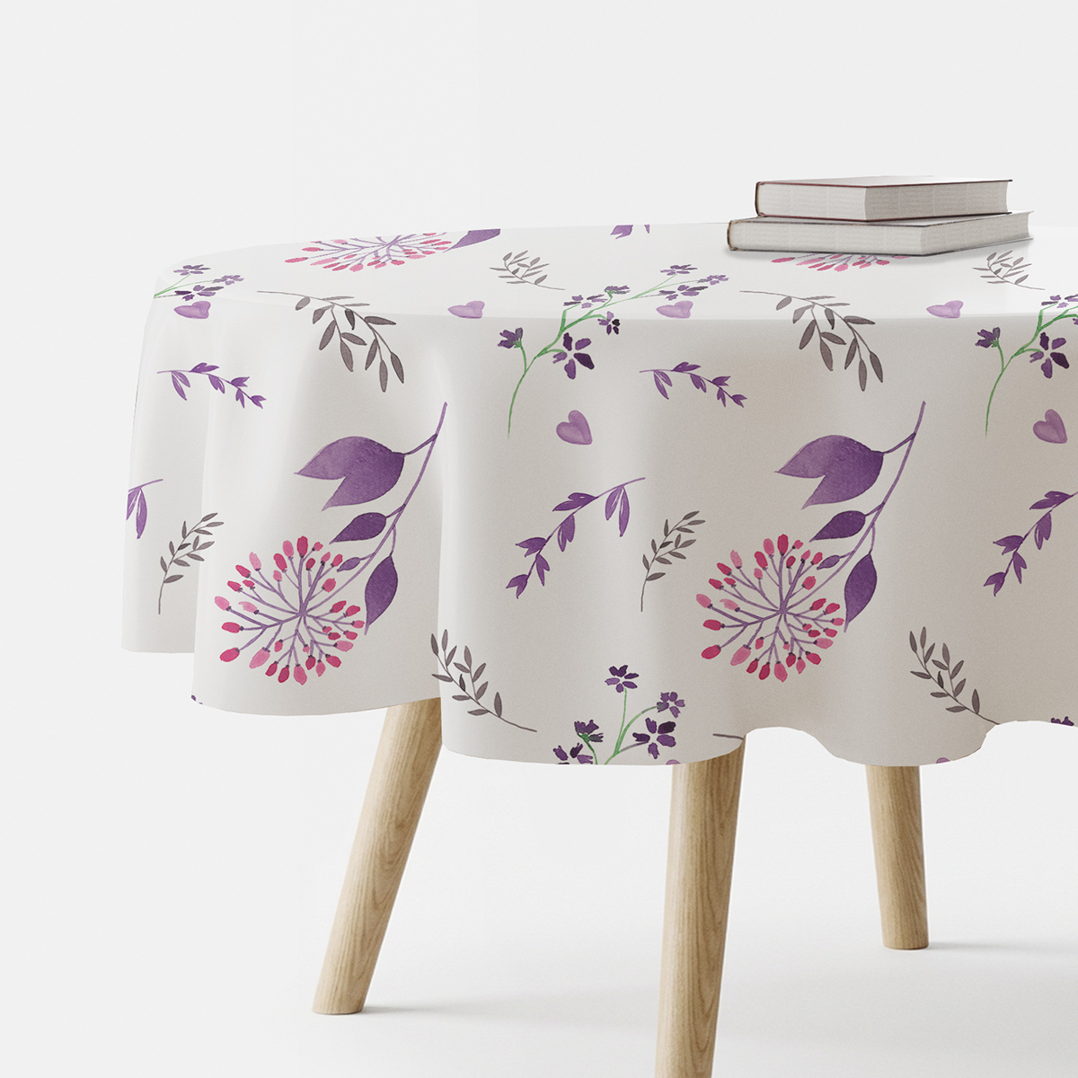 okrągły obrus z akwarelowym wzorem gałązek i serduszek na białym tle, widok boczny stołu z książkami