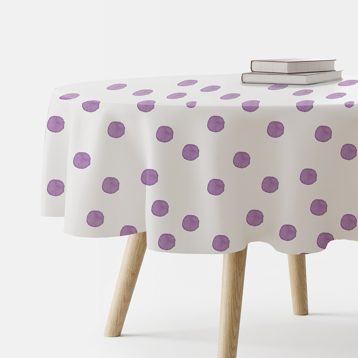okrągły obrus na stole z fioletowymi akwarelowymi kropkami, ujęcie z boku z książkami na blacie