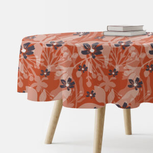 Okrągły obrus w ceglastym kolorze z delikatnymi kwiatami rozłożony na stole