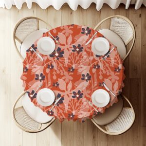 Widok z góry na okrągły stół ułożony z obrusem w motyw ceglastych kwiatów