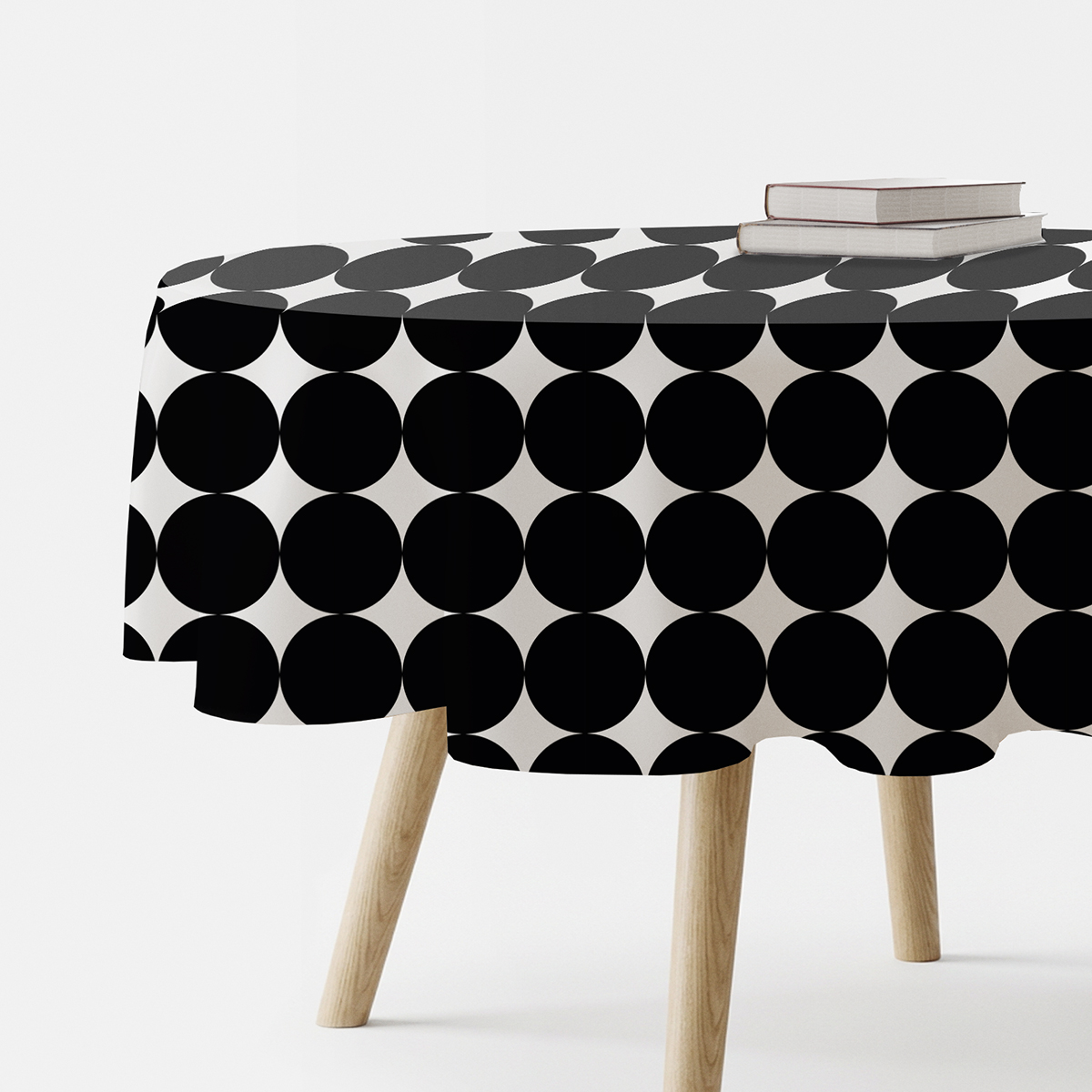 okrągły obrus z dużymi czarnymi kółkami na białym tle, ujęcie z boku na stole z drewnianymi nogami