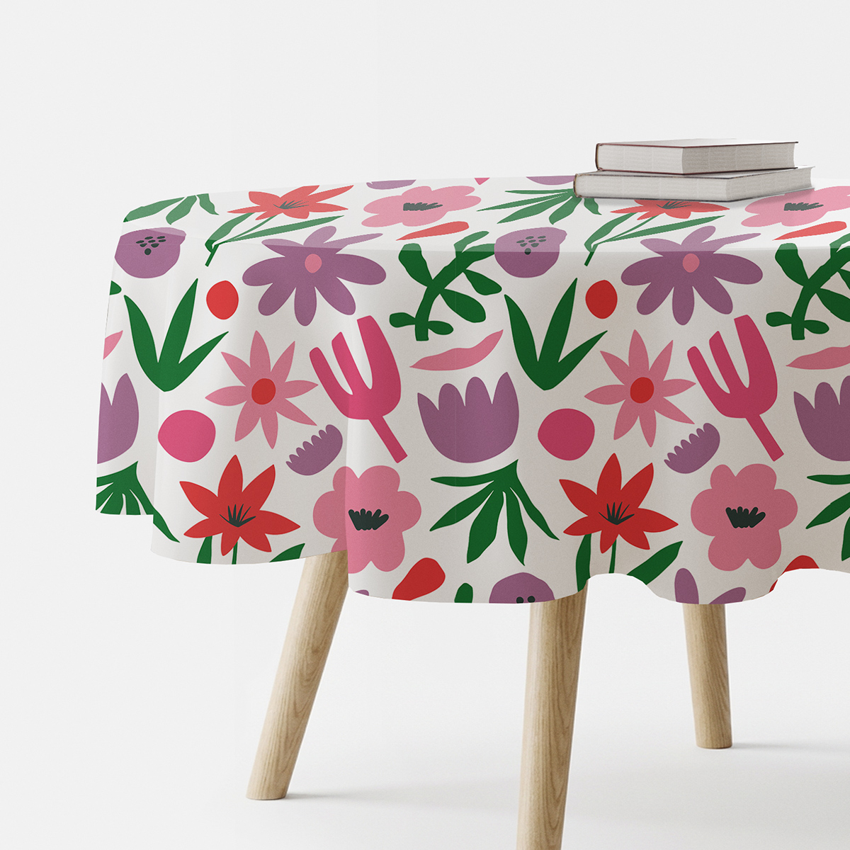 Okrągły stół nakryty obrusem z dużym, kolorowym motywem kwiatowym na białym tle