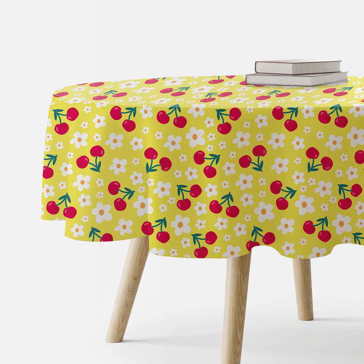 Okrągły żółty obrus na stole z motywem czerwonych wiśni i białych stokrotek