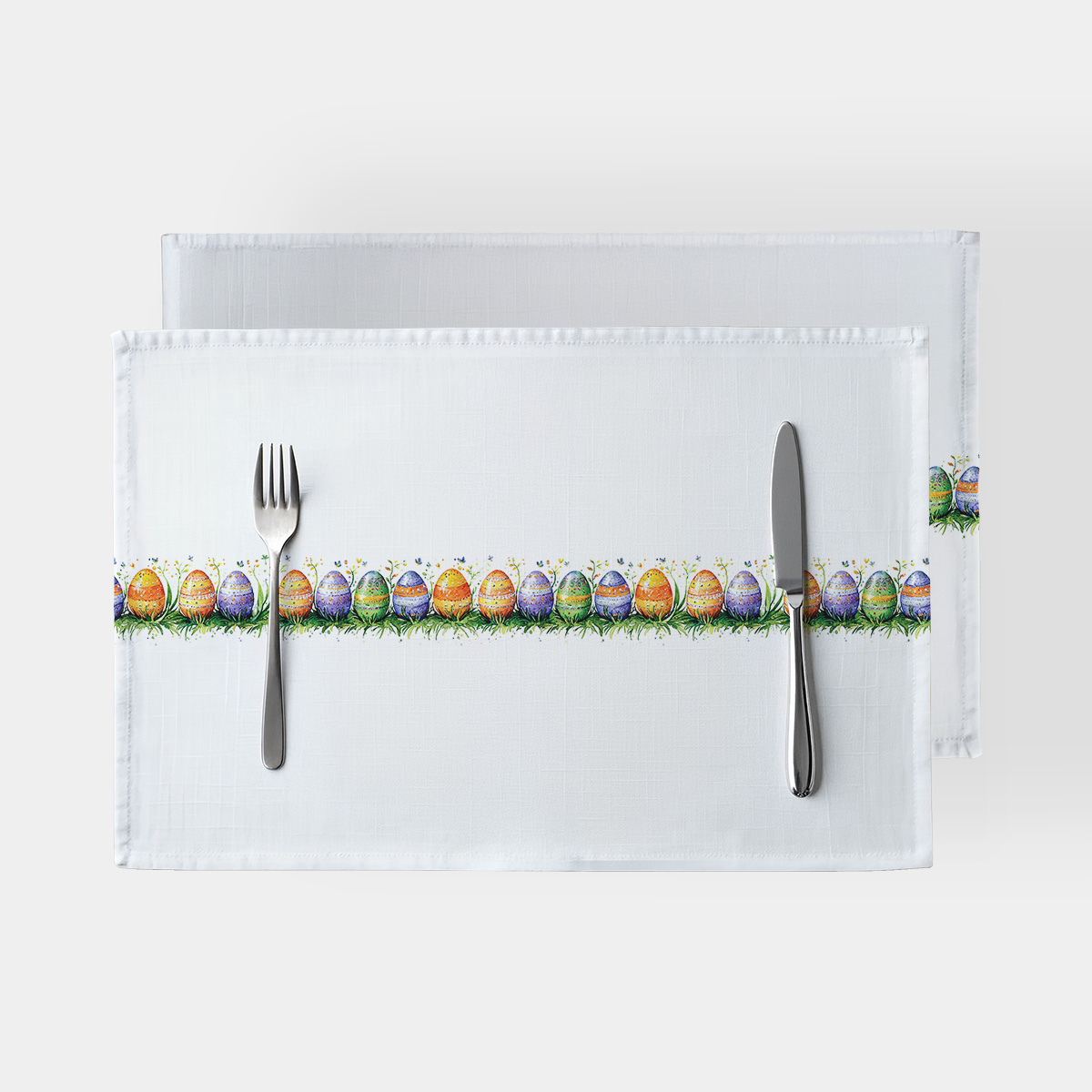 biała podkładka z poziomym pasem akwarelowych pisanek w trawie