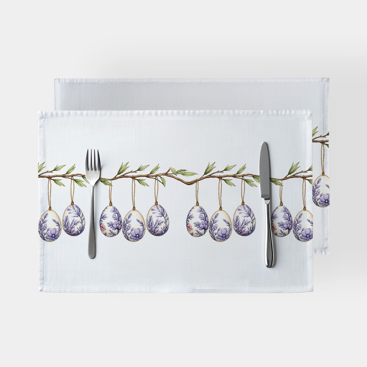 główne ujęcie białej podkładki z gałązką i wiszącymi pisankami w lawendowych wzorach