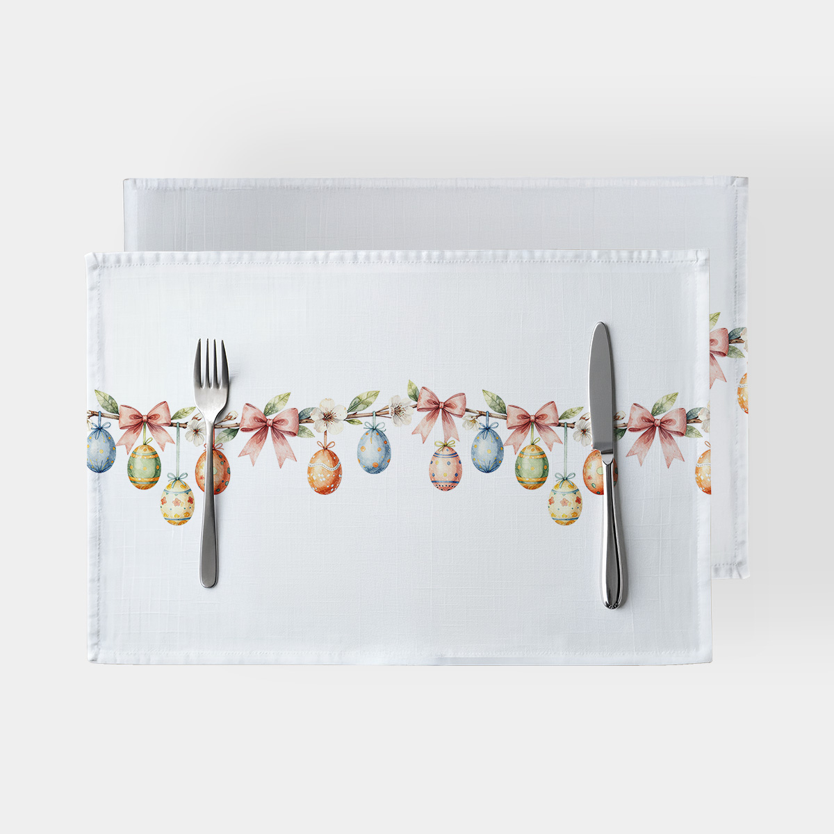 biała podkładka z motywem zawieszonych pisanek i różowych kokardek na gałązce, widok z góry