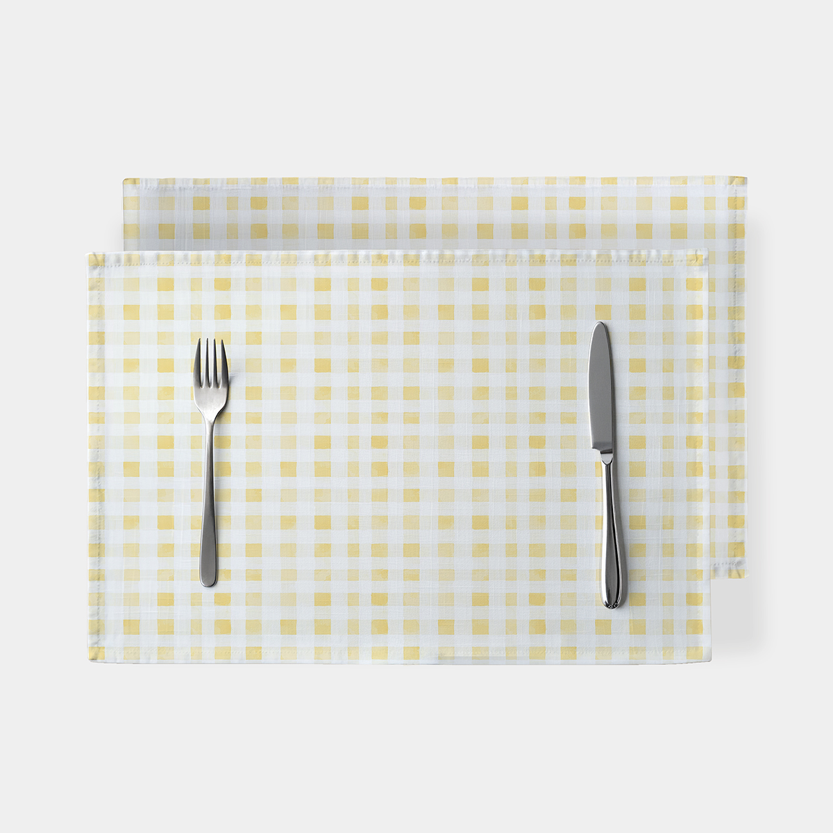 Widok z góry na pojedynczą podkładkę w żółtą kratkę z widocznymi sztućcami