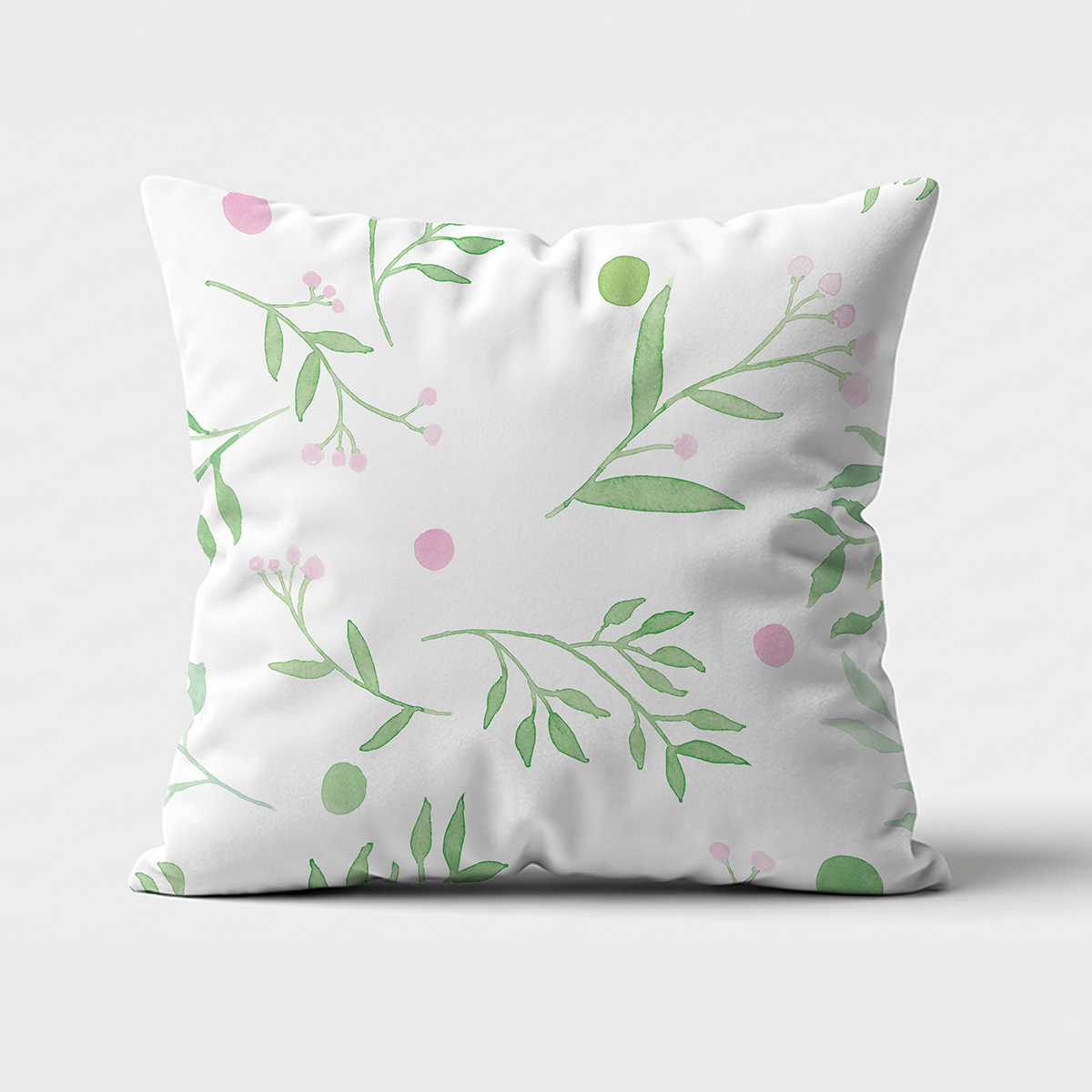 biała poduszka z akwarelowymi zielonymi gałązkami i różowymi kropkami na jasnym tle