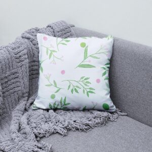 poduszka ozdobna z akwarelowym wzorem ułożona na szarej sofie obok pledu