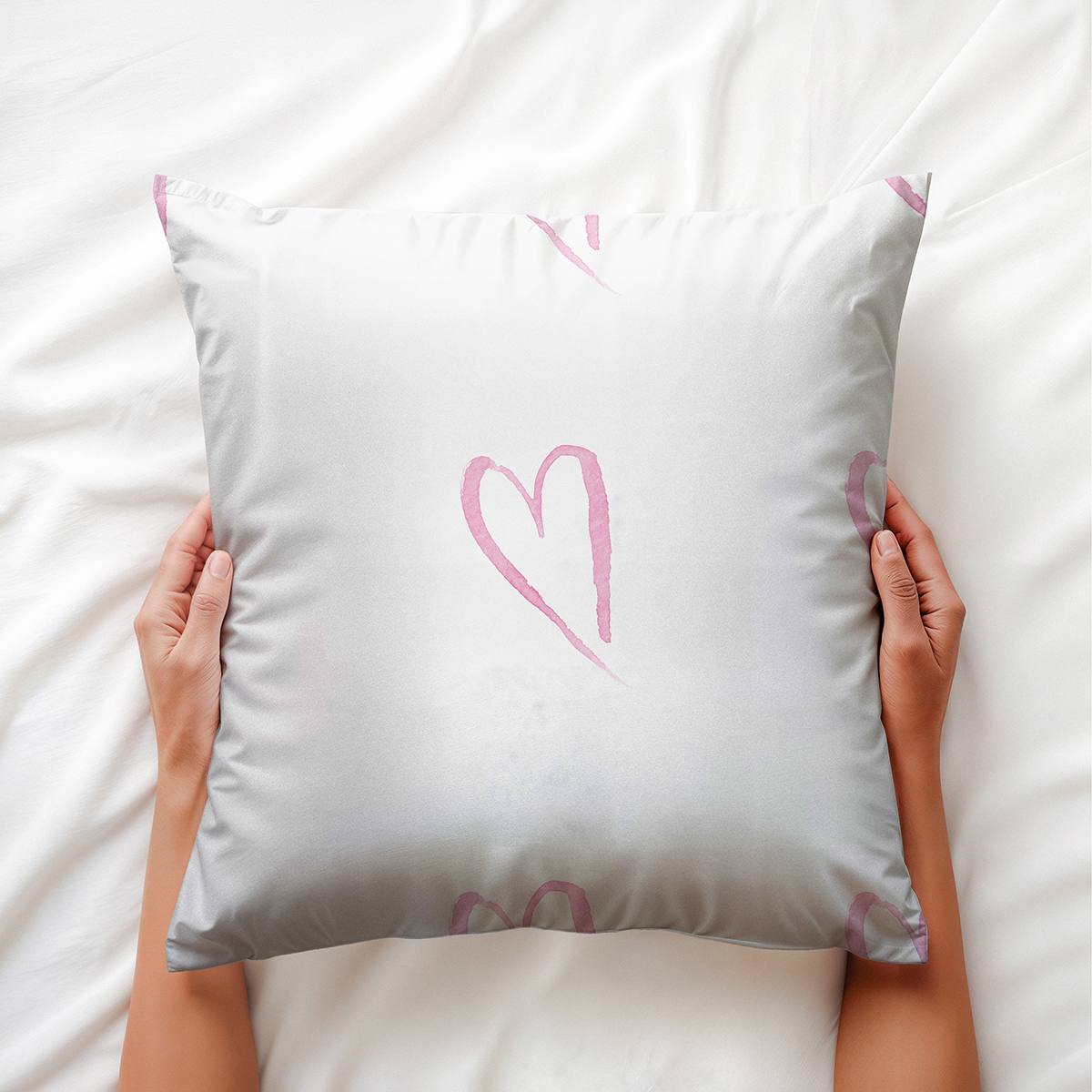 ręce trzymają poduszkę z różowym akwarelowym motywem serca zbliżenie na wzór