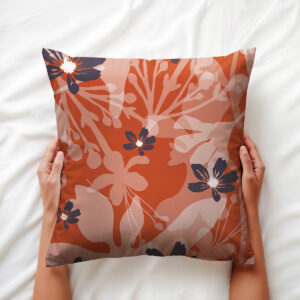 Ręce trzymające poduszkę z motywem kwiatowym na białej pościeli, widoczne detale wzoru