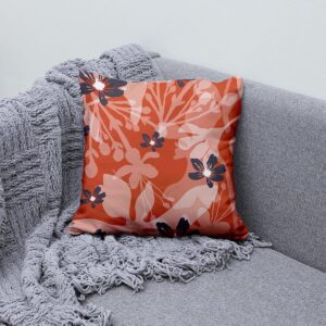 Poduszka z roślinnym motywem ułożona na szarej kanapie obok pledu