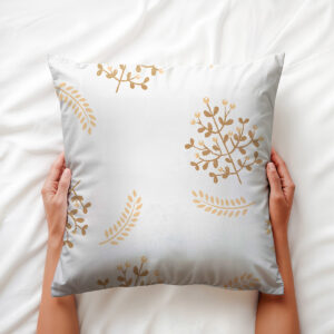 Dłoń trzymająca poduszkę z dekoracyjnym motywem złotych listków — ujęcie aranżacyjne
