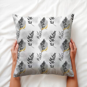 Zbliżenie na poduszkę trzymaną w dłoniach, widoczne detale gałązek i złote połyskujące akcenty