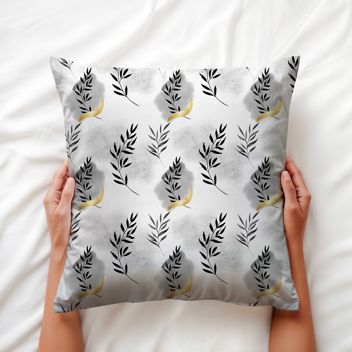 Zbliżenie na poduszkę trzymaną w dłoniach, widoczne detale gałązek i złote połyskujące akcenty