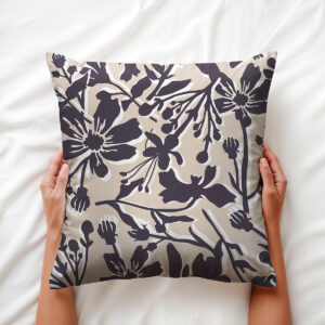 Ręce trzymające poduszkę z delikatnym kwiatowym wzorem na białej pościeli, widok z góry