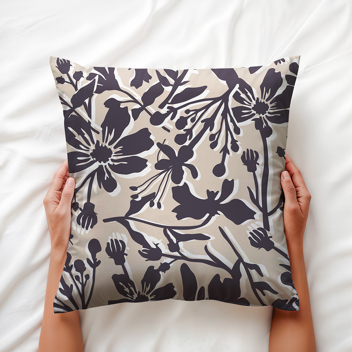 Ręce trzymające poduszkę z delikatnym kwiatowym wzorem na białej pościeli, widok z góry