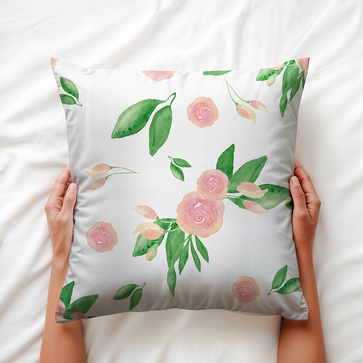 Ręce trzymające miękką poduszkę ozdobną z akwarelowym wzorem różyczek