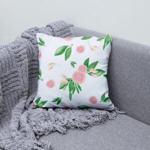 Poduszka dekoracyjna z delikatnymi różyczkami ułożona na szarym narożniku obok pledu