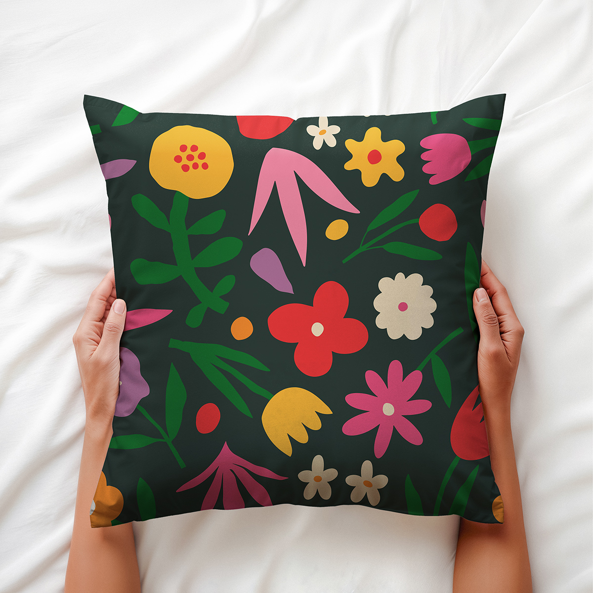 Poduszka trzymana w dłoniach z widocznym nadrukiem czerwonych, różowych i żółtych kwiatów