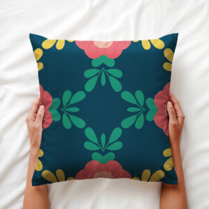 Ręce trzymające poduszkę, detal symetrycznego wzoru z liśćmi i koralowymi kwiatami