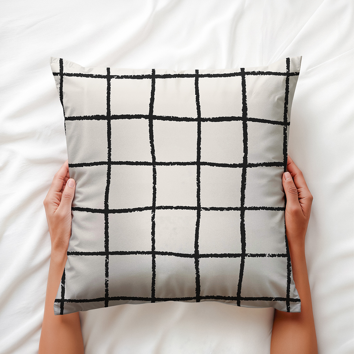 Widok poduszki trzymanej w dłoniach na białej pościeli ukazujący detal wzoru