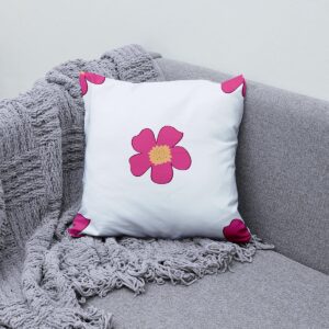 Poduszka dekoracyjna ułożona na kanapie obok pledu, aranżacja wnętrza z kwiatowym akcentem