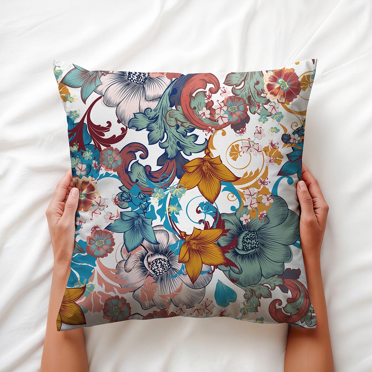 Zbliżenie na detal nadruku i kolorystykę poduszki trzymanej w dłoniach, widoczne rysunkowe kwiaty i zawijasy