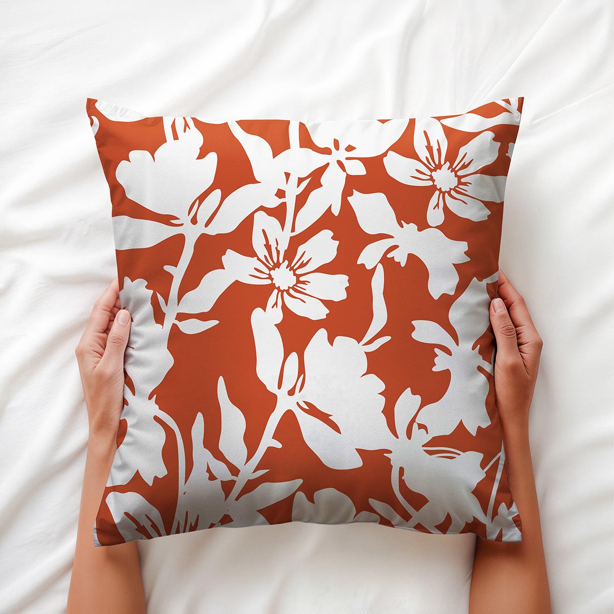 Poduszka trzymana w dłoniach na białej pościeli z widocznym kontrastem wzoru i tła