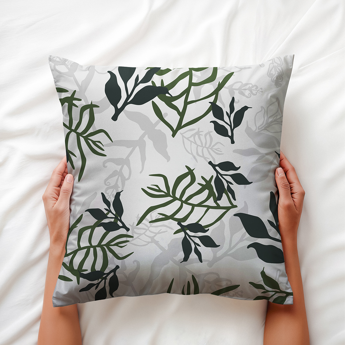 Poduszka trzymana w dłoniach, widoczny wzór liści i detal nadruku