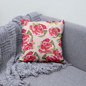 Poduszka dekoracyjna z malowanymi różami ułożona na sofie obok szarego koca
