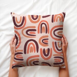 Poduszka trzymana w dłoniach, widoczny malowany motyw półokrągłych pociągnięć pędzla