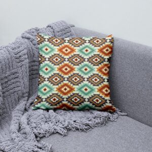 Poduszka z azteckim motywem ułożona na kanapie obok szarego koca, aranżacja wnętrza