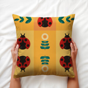 Osoba trzymająca poduszkę z motywem biedronek i stylizowanych kwiatów, ujęcie z bliska