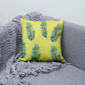 Poduszka dekoracyjna z liśćmi palmowymi ustawiona na szarej kanapie z narzutą