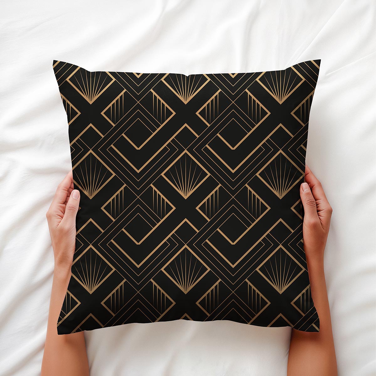 Poduszka z motywem art deco trzymana w dłoniach na jasnej pościeli, detal wzoru