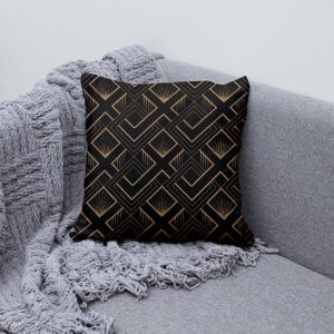 Poduszka z złotym geometrycznym wzorem ustawiona na szarej sofie obok pledu