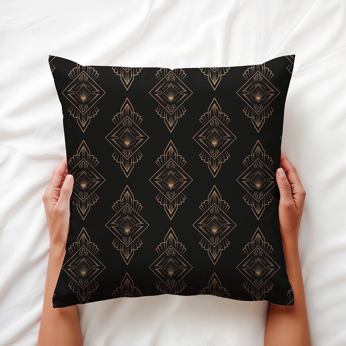 Aranżacyjne ujęcie: ręce trzymają poduszkę na białej pościeli, widoczne złote ornamenty