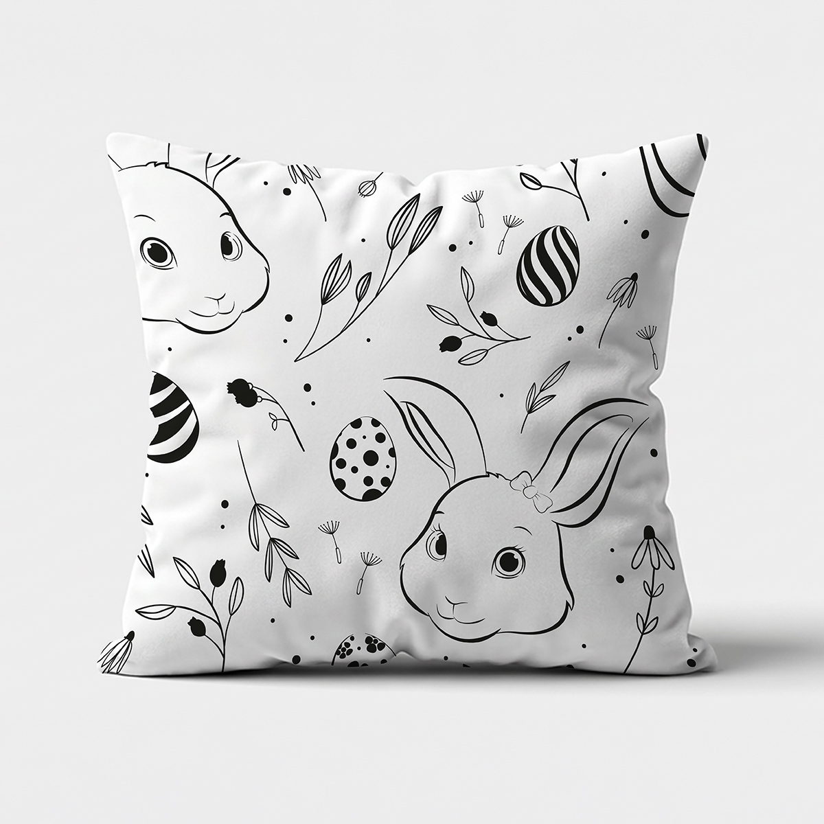 poduszka z czarno-białym wzorem króliczków i pisanek, widok z przodu na jasnym tle